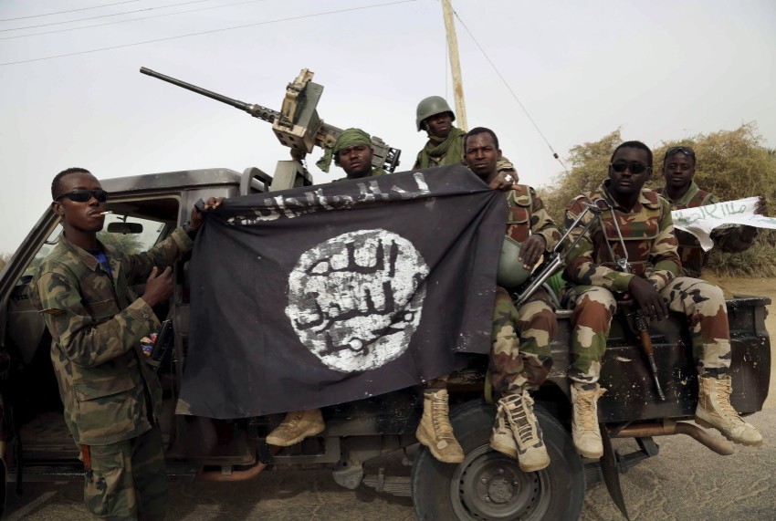 Nigerien soldiers hold up a Boko Haram flag that they had seized in the recently retaken town of Damasak, Nigeria
