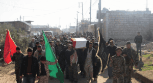 Photo 2. Funeral procession held in Zahraa for two Syrian Shiites killed in Aleppo operation, Dec. 7. Imam al Hujja Regiment flag on left.